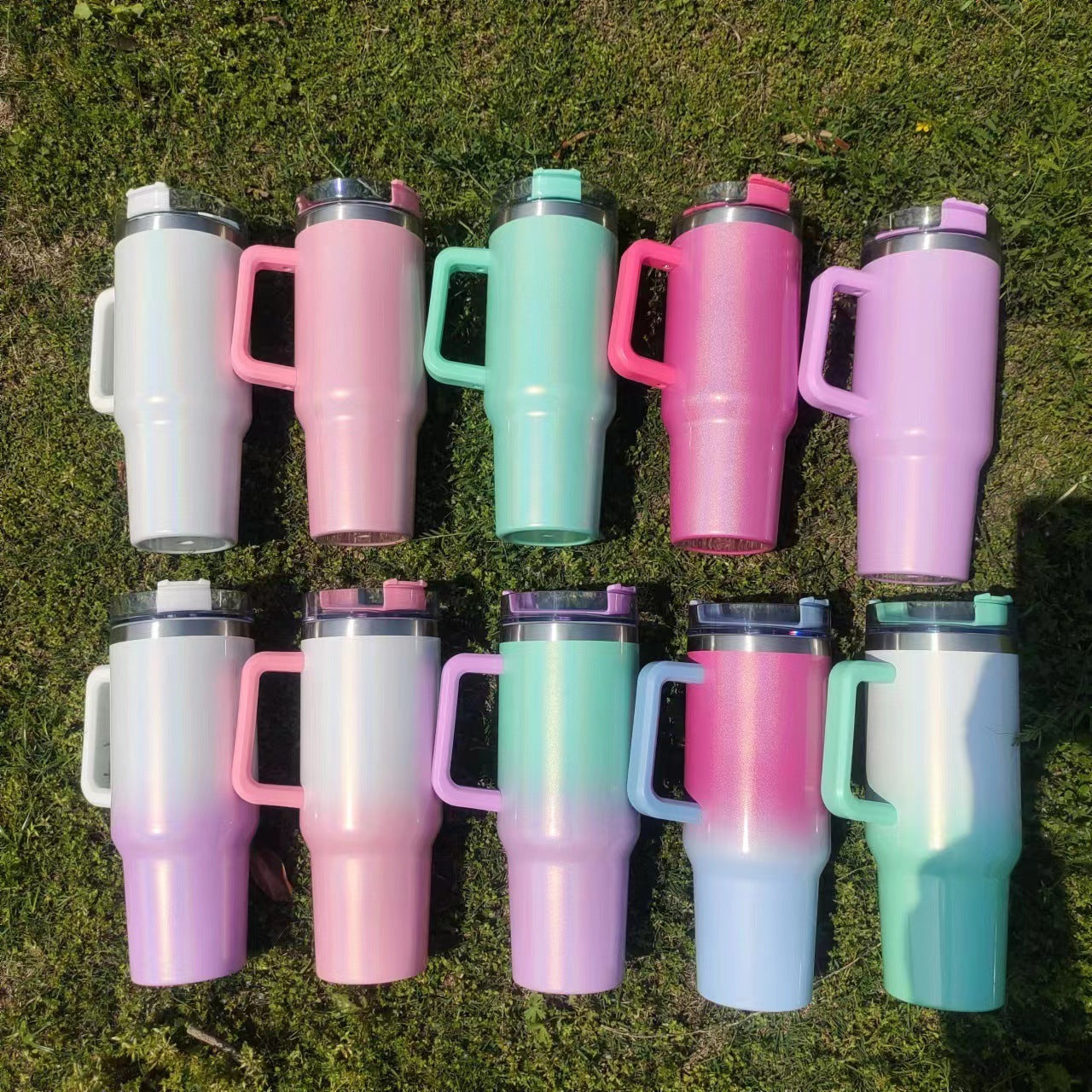 Set of colorful tumblers with gradient designs on a grassy background
